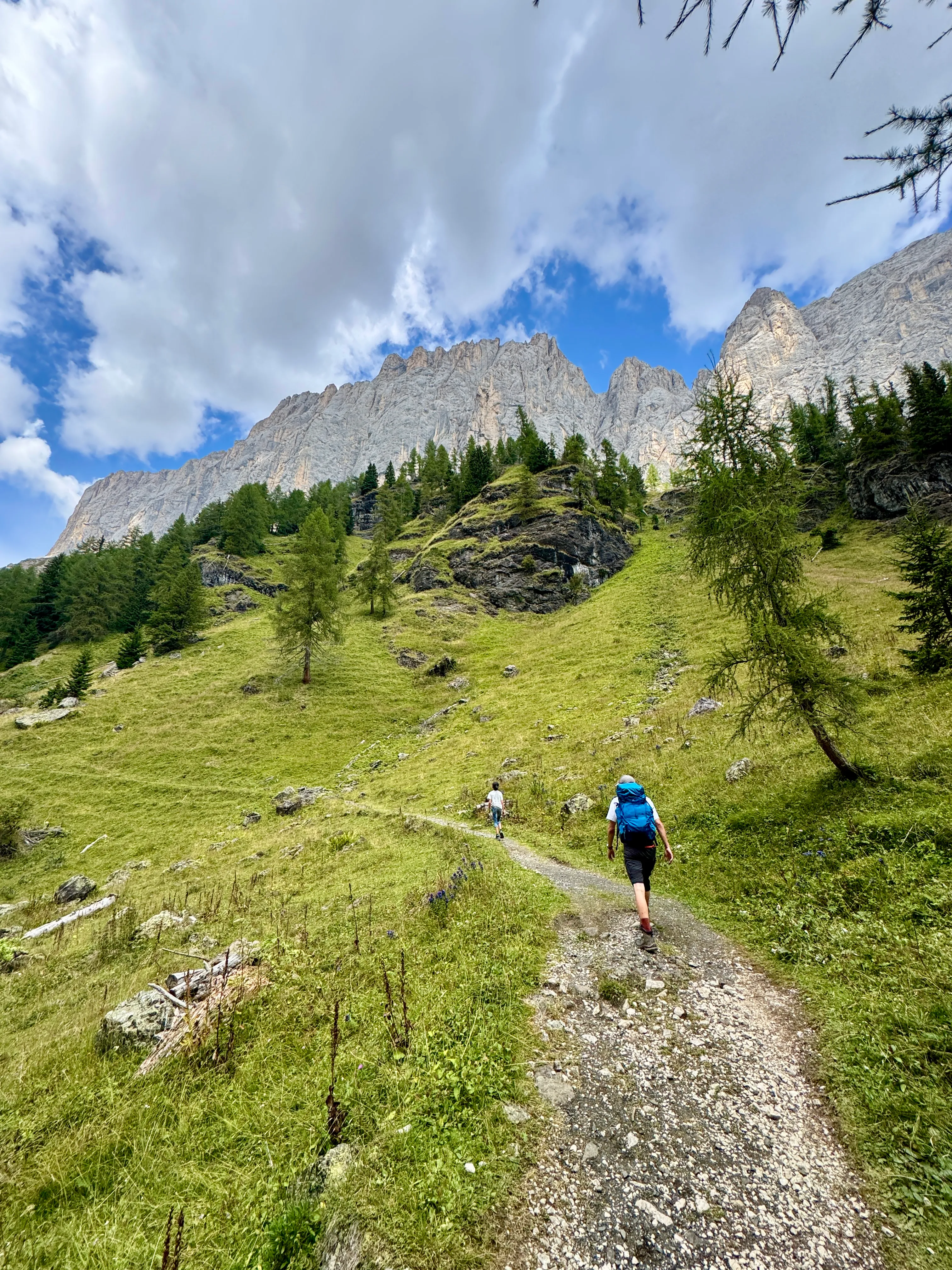 Hikers walking a trail toward jagged Dolomite peaks near Rifugio Falier in the Val Ombretta