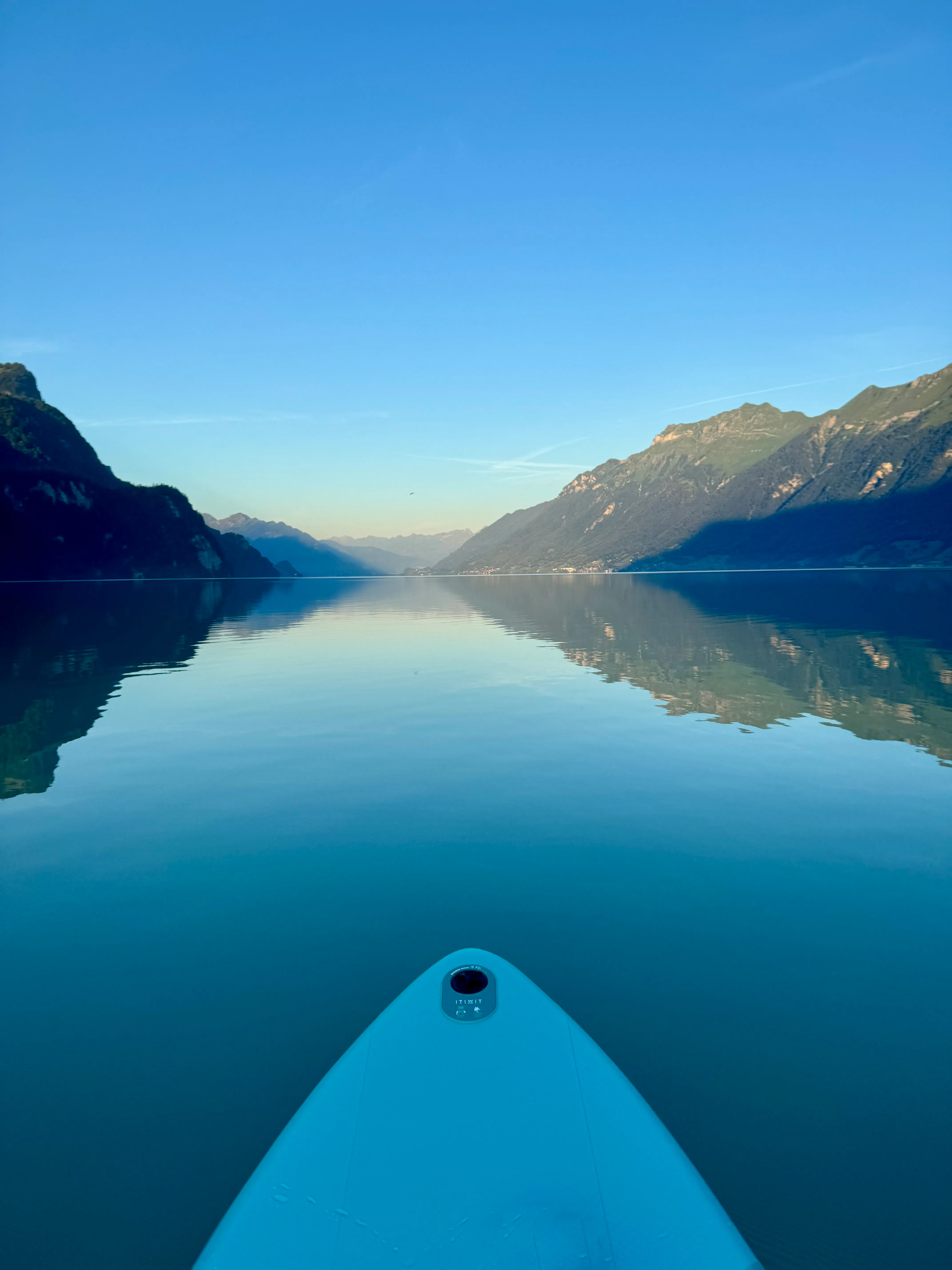 Paddleboarding on the glassy, mirror-calm water of Lake Brienz with mountains reflected on both sides