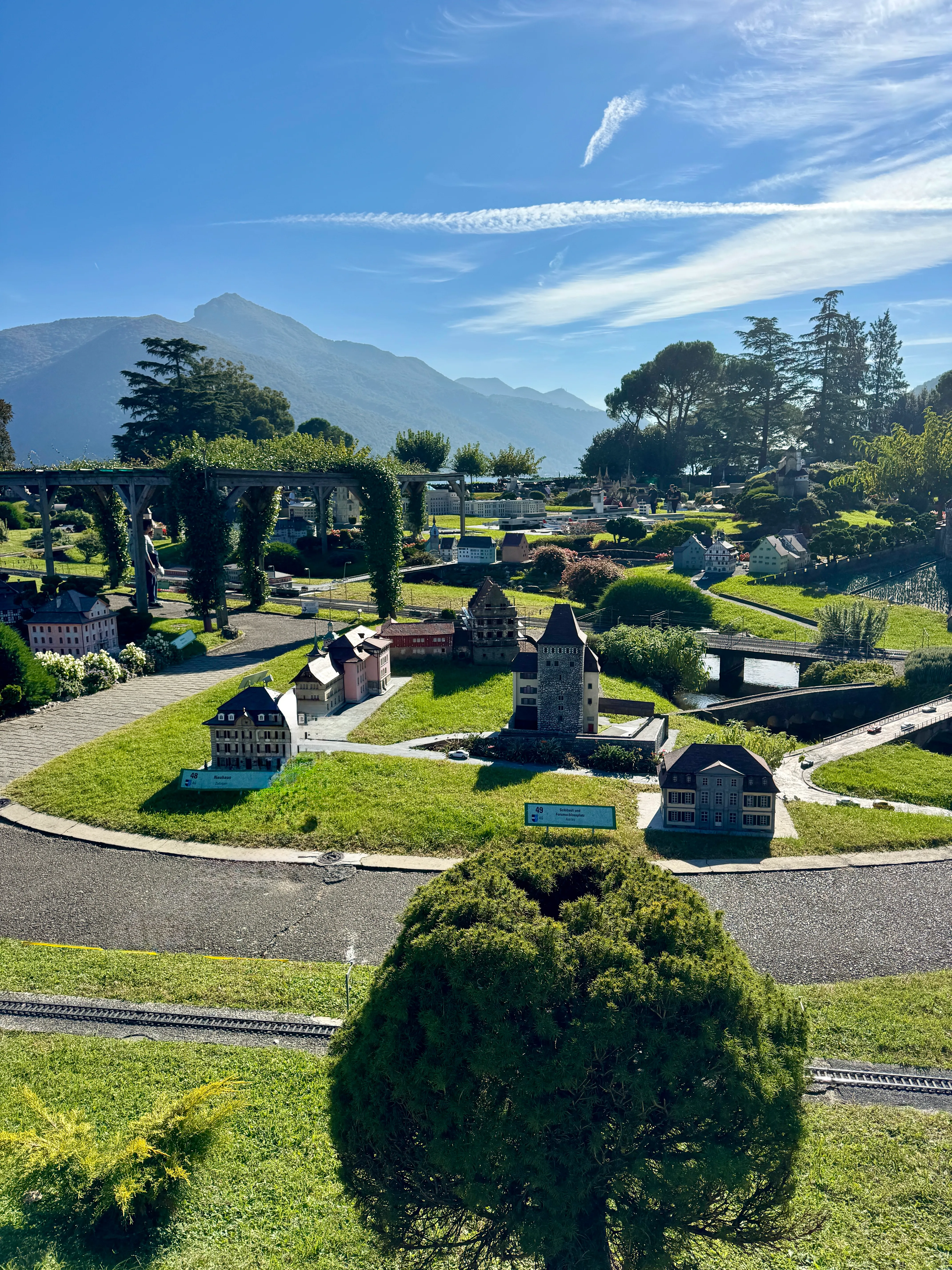 Miniature model buildings and gardens at Swissminiatur, with mountains in the background