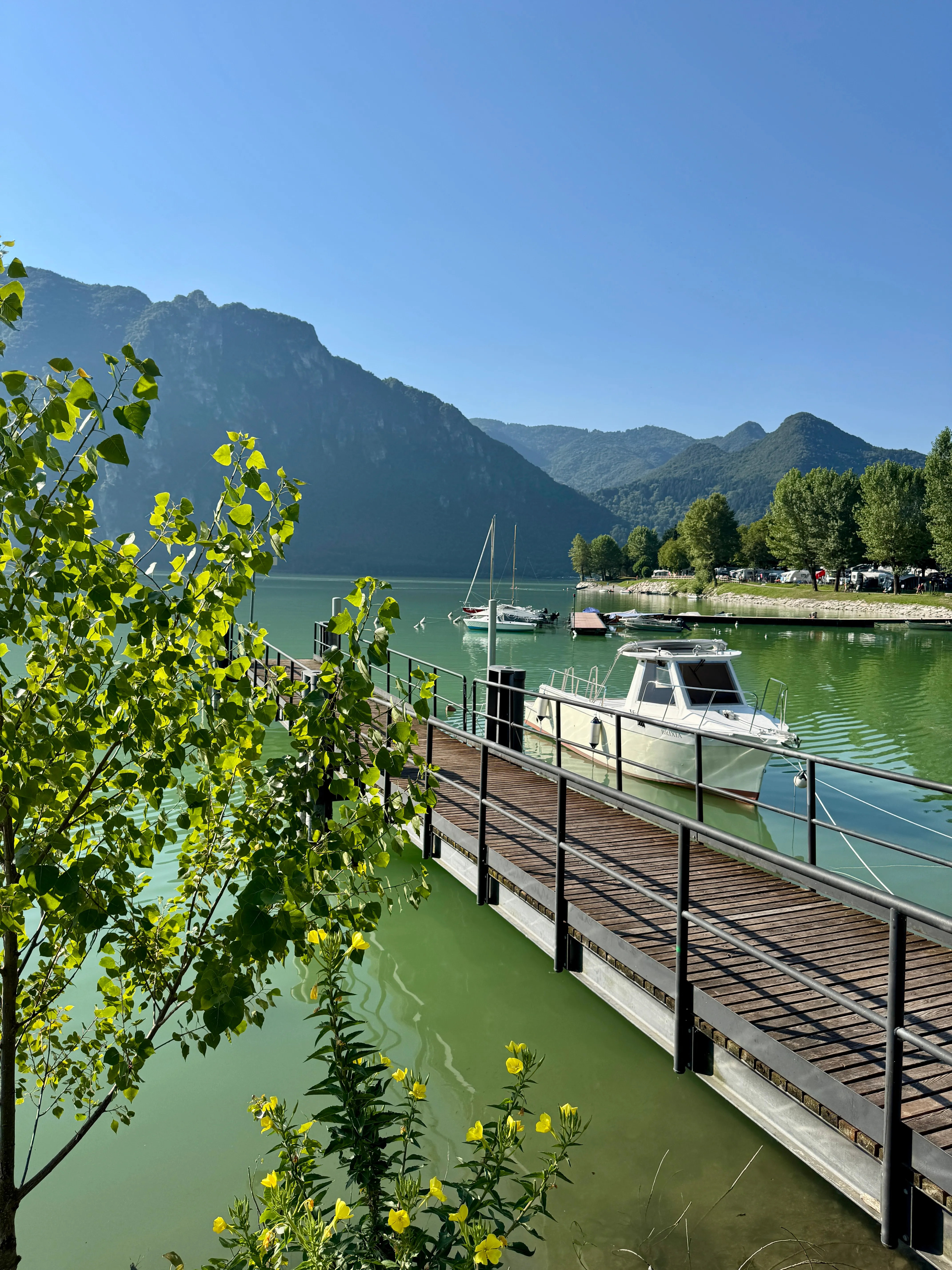 Boats moored at a wooden jetty on Lago d’Idro with mountains in the background