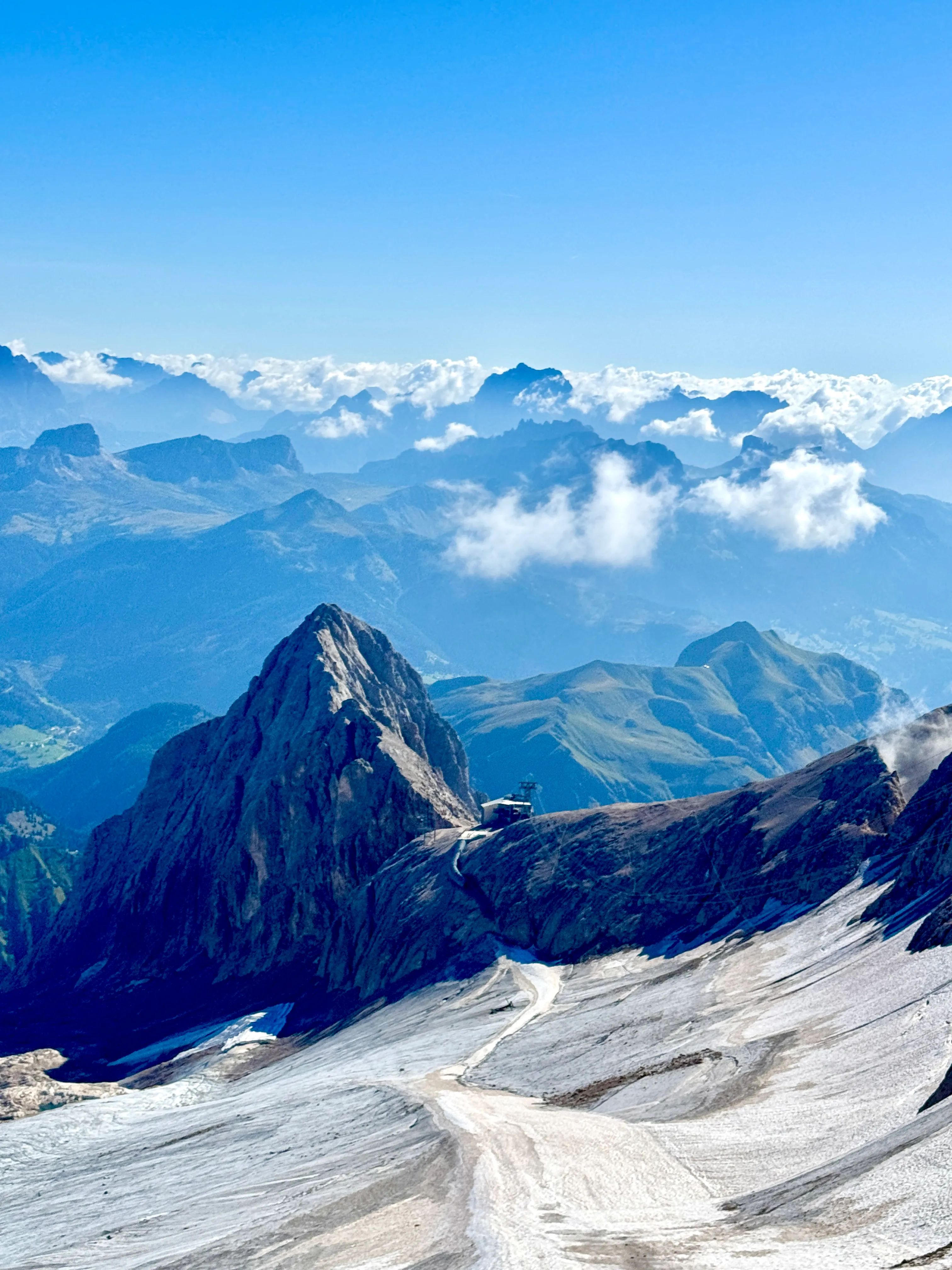 View across the Marmolada glacier to a rocky peak and cable car station at Punta Rocca