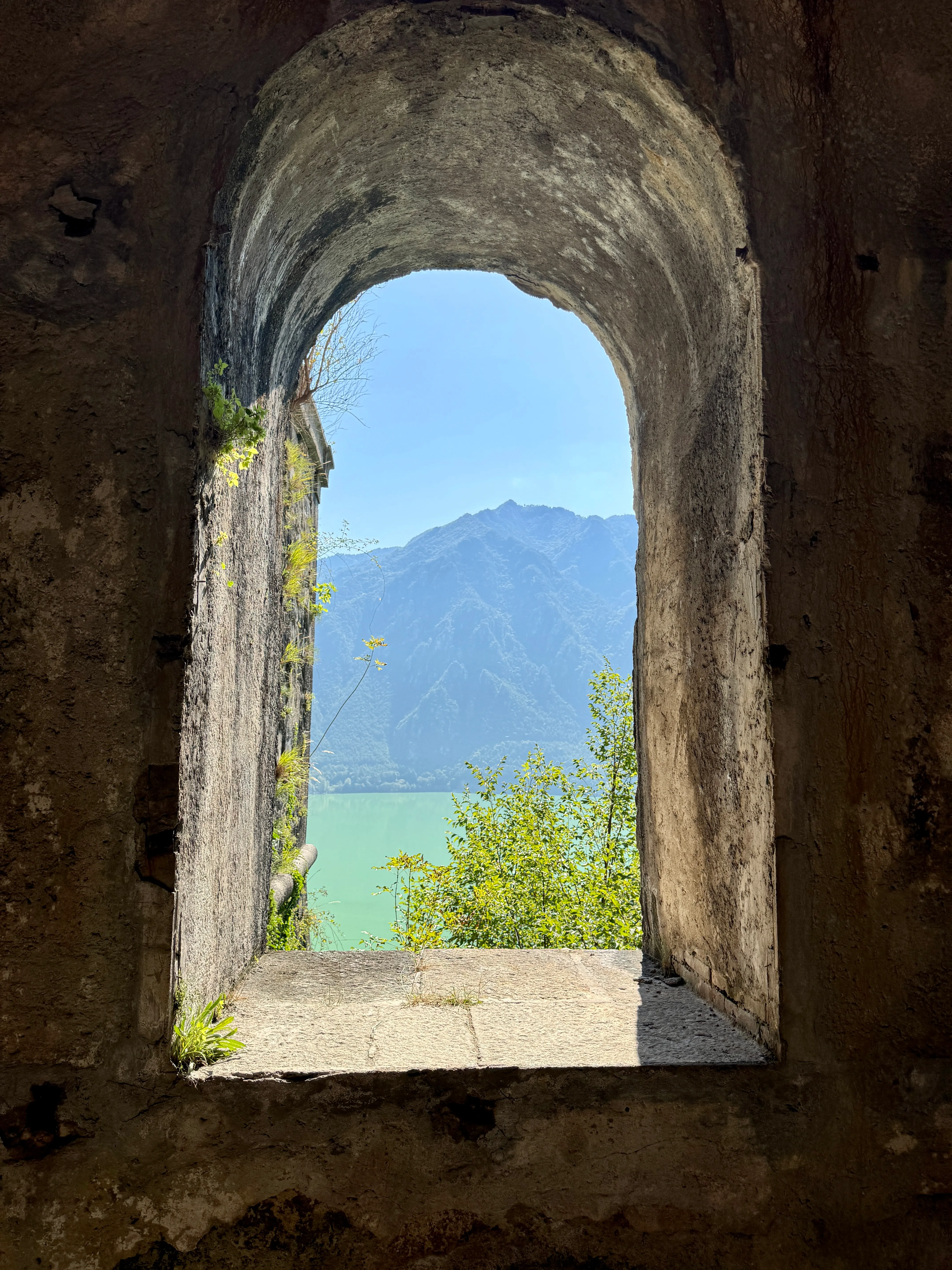 View of Lago d’Idro and the mountains through an old stone window at the Rocca d’Anfo fortress
