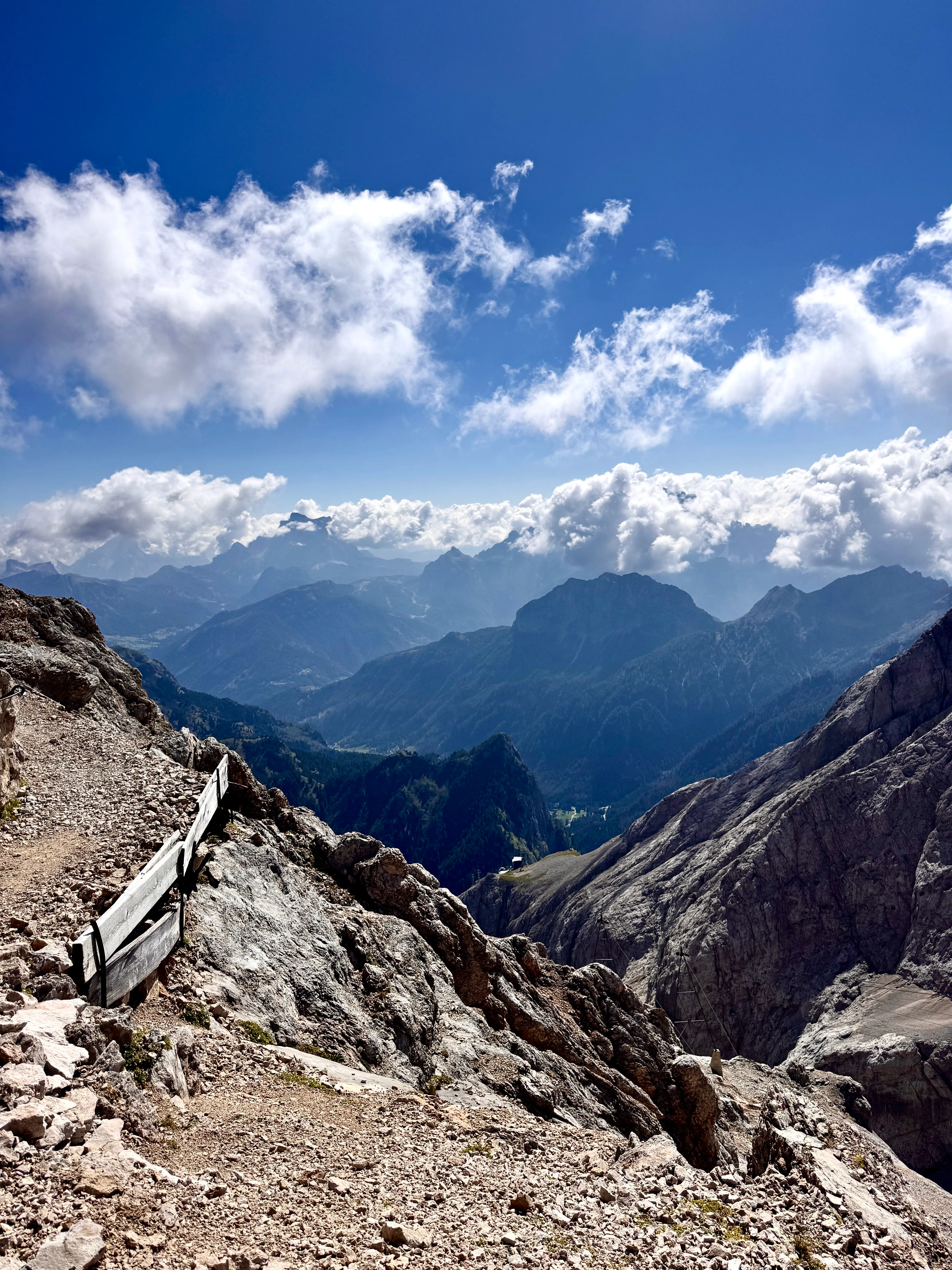 Rocky path near the summit of Marmolada with panoramic views across cloud-wreathed Dolomite peaks