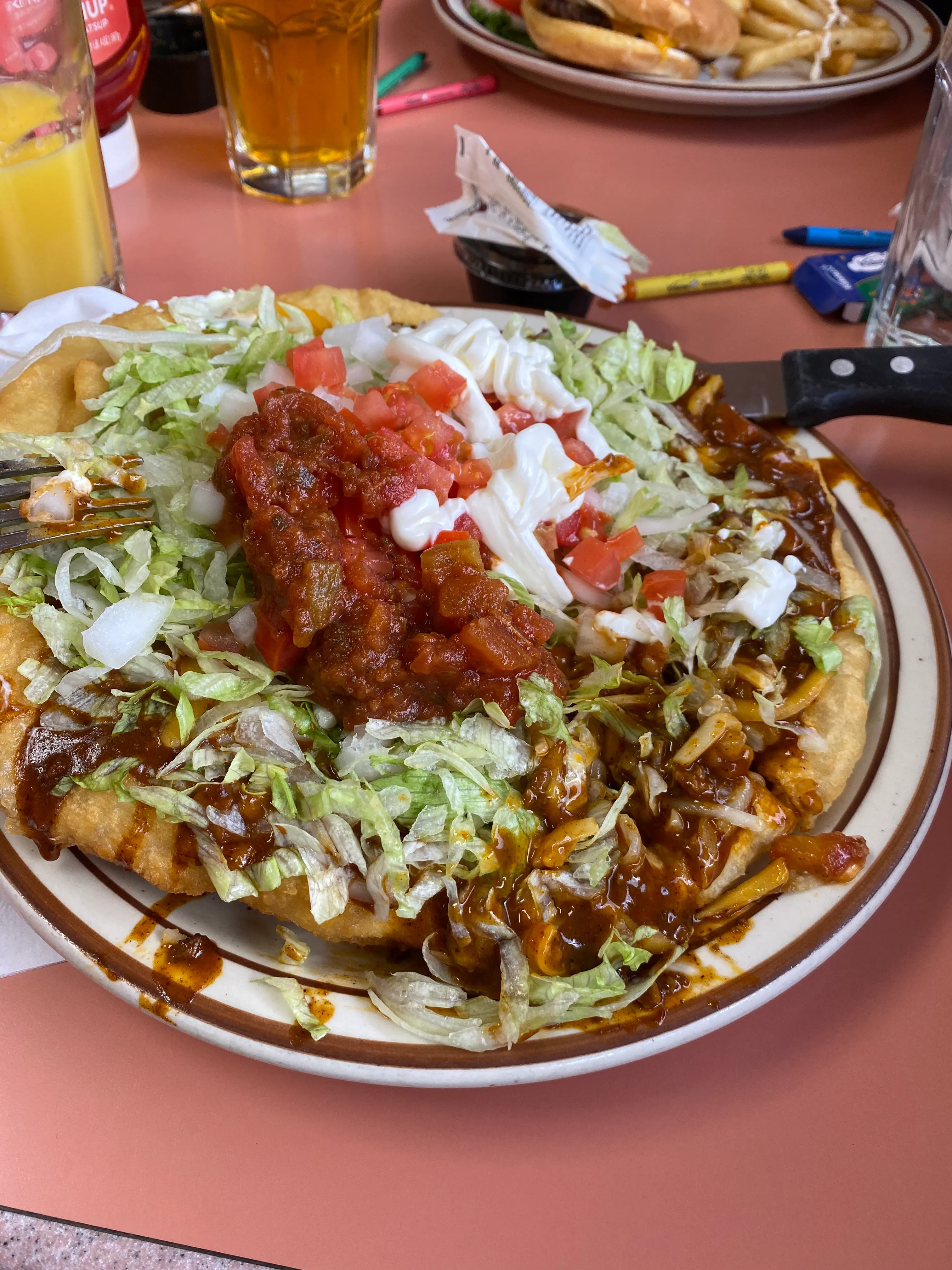 A loaded Navajo taco topped with chilli, lettuce, tomato, salsa and sour cream