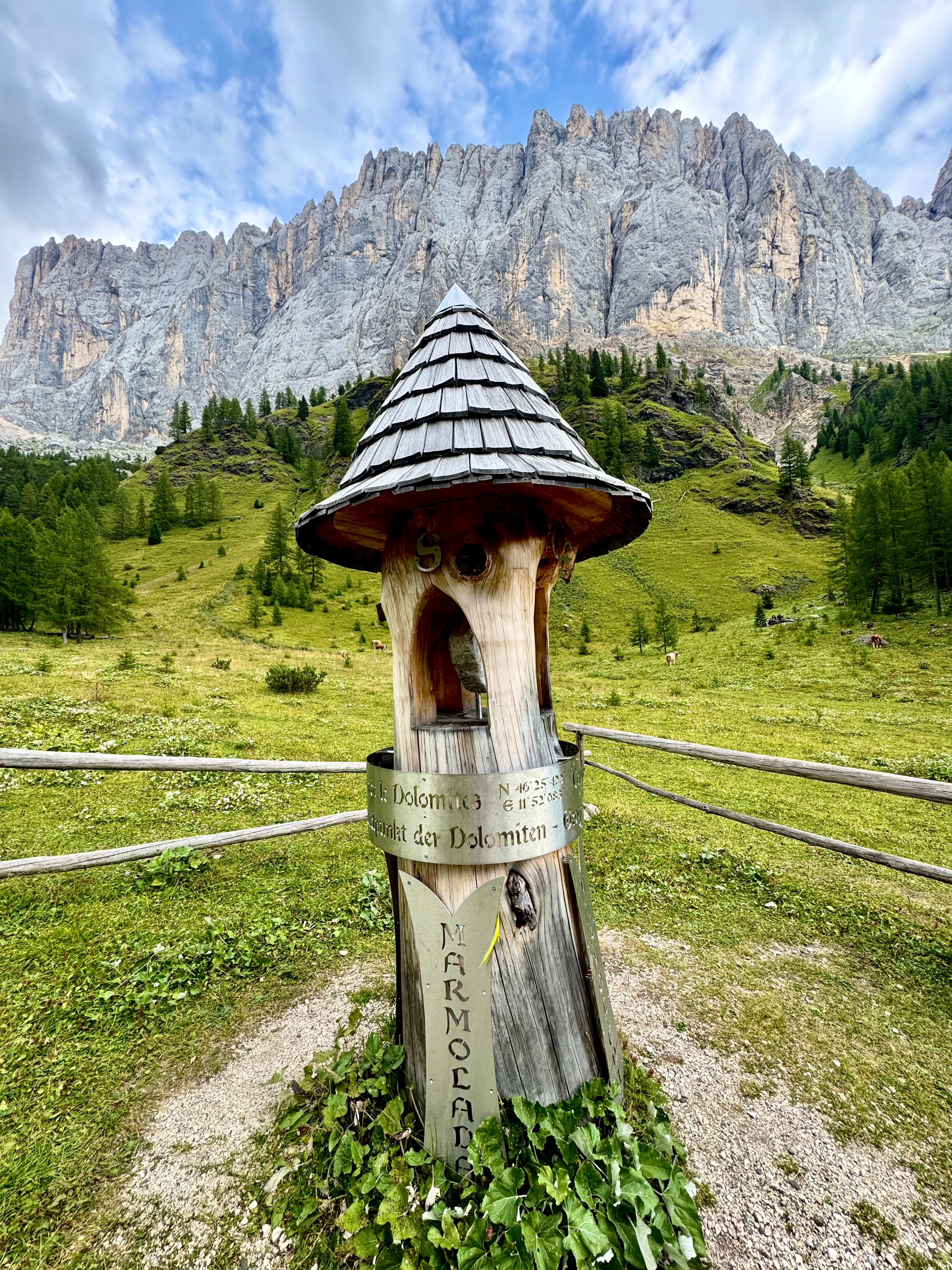 Wooden totem marking the geographical centre of the Dolomites, standing in a grassy meadow