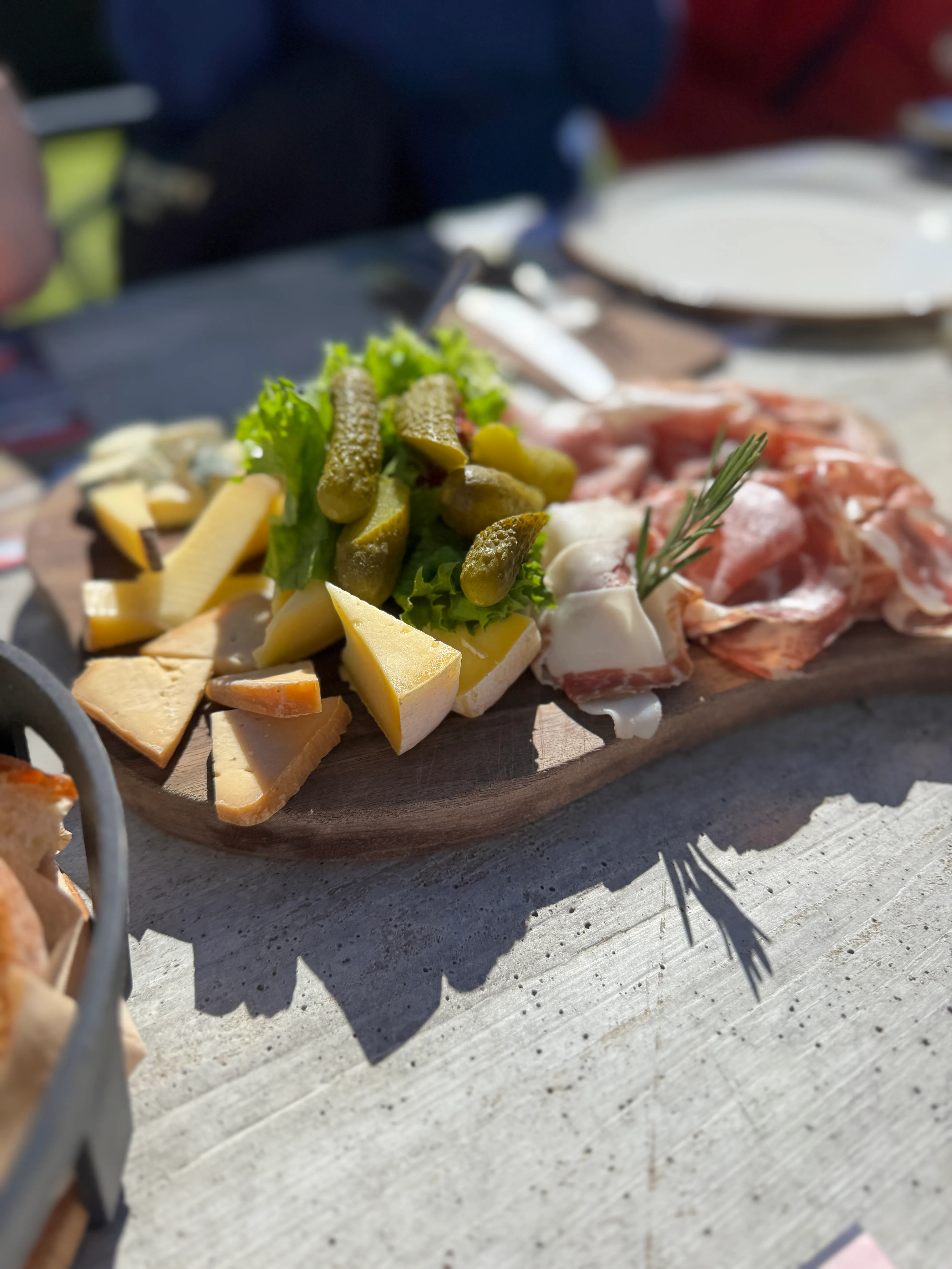 A Ticino cheese and charcuterie board with gherkins, cured meats and rosemary at a mountain restaurant