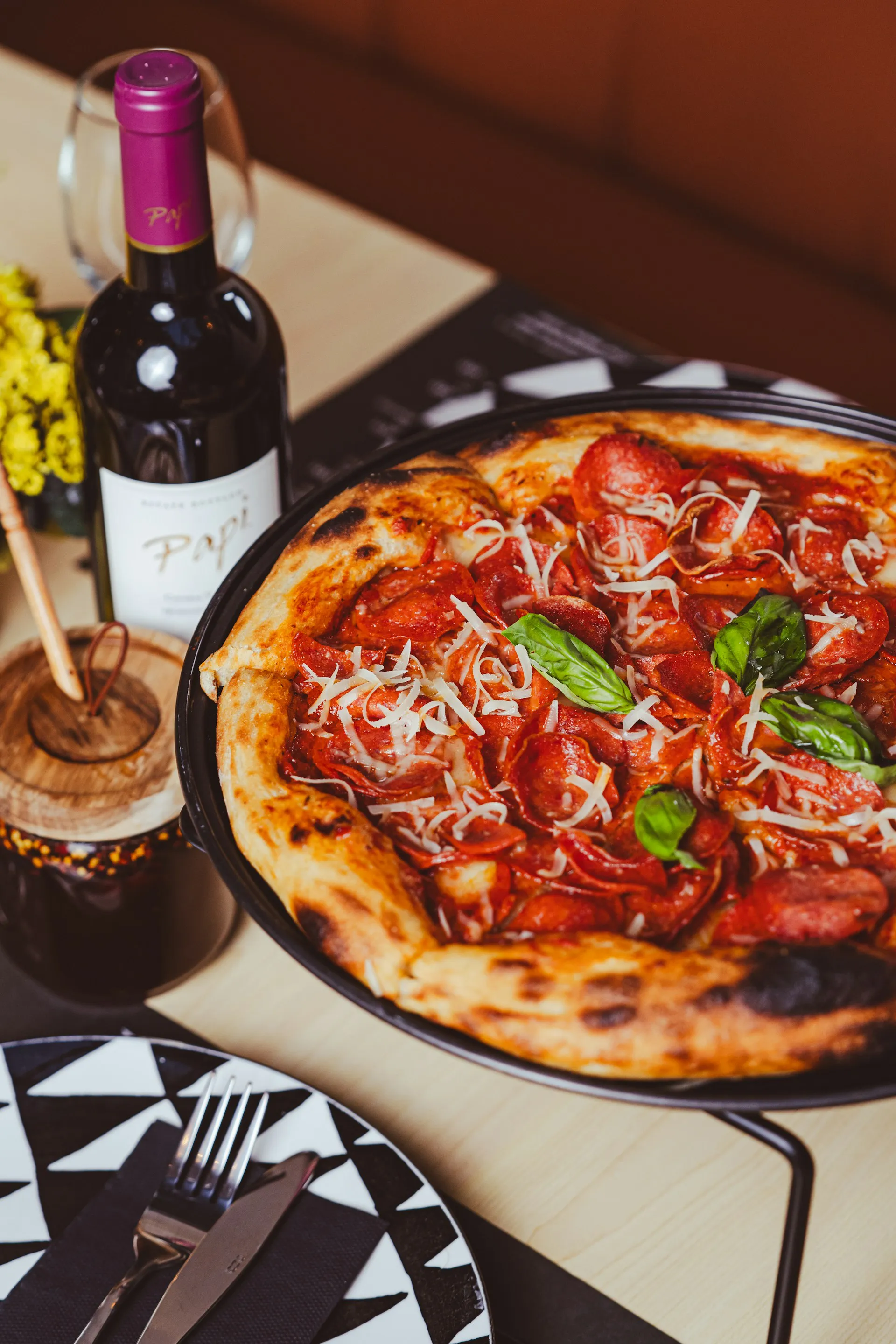 A pepperoni and basil pizza with a bottle of red wine on a Rome restaurant table